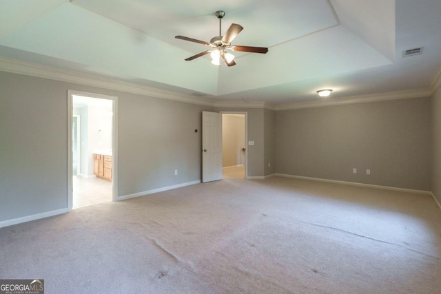 carpeted empty room featuring ceiling fan, a raised ceiling, and ornamental molding