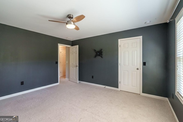 unfurnished bedroom featuring light carpet, multiple windows, and ceiling fan