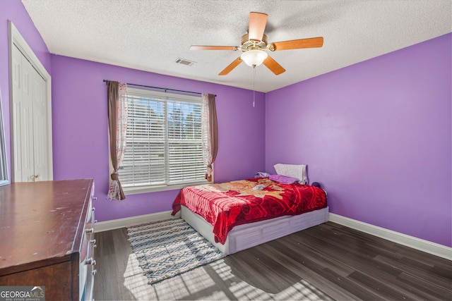 bedroom with ceiling fan, a textured ceiling, and dark hardwood / wood-style floors