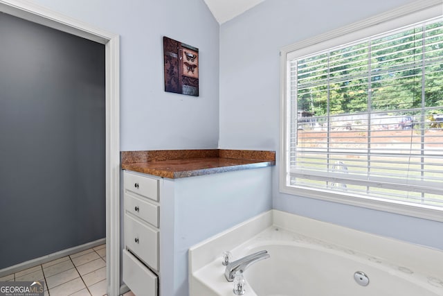 bathroom with a wealth of natural light, lofted ceiling, a bathtub, and tile patterned flooring