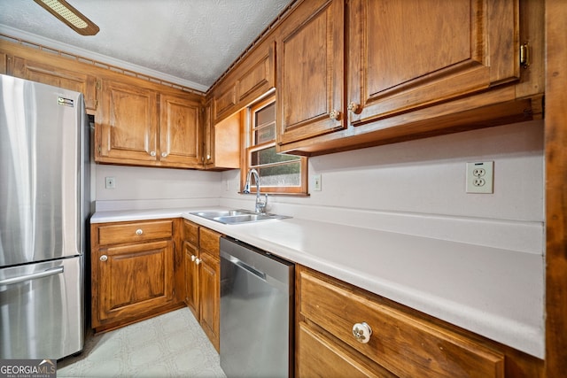 kitchen with crown molding, a textured ceiling, stainless steel appliances, and sink