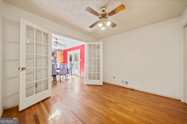 spare room featuring french doors, ceiling fan, a textured ceiling, and hardwood / wood-style floors