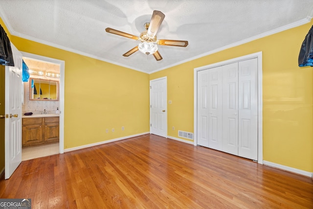 unfurnished bedroom with ceiling fan, a textured ceiling, ornamental molding, and light hardwood / wood-style floors