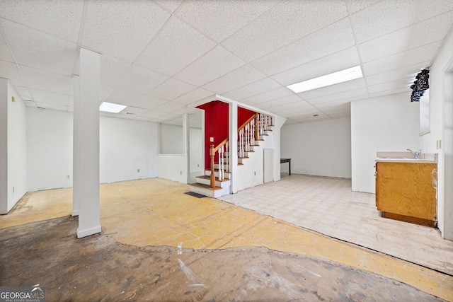 basement with a paneled ceiling and sink