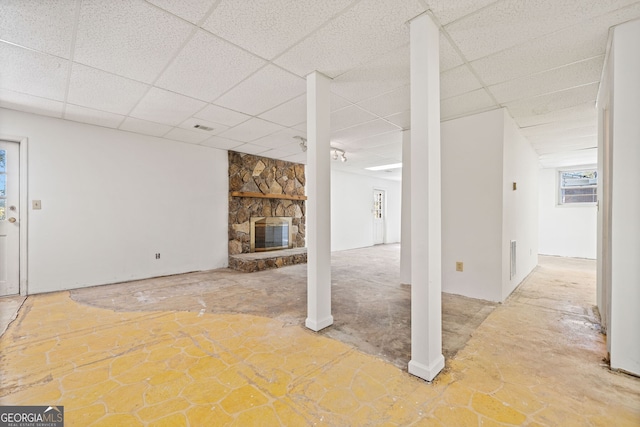 basement with a paneled ceiling and a fireplace