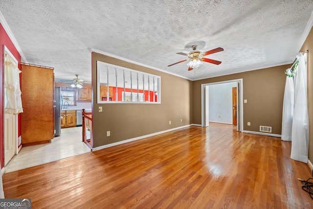 unfurnished room featuring crown molding, light hardwood / wood-style flooring, a textured ceiling, and ceiling fan