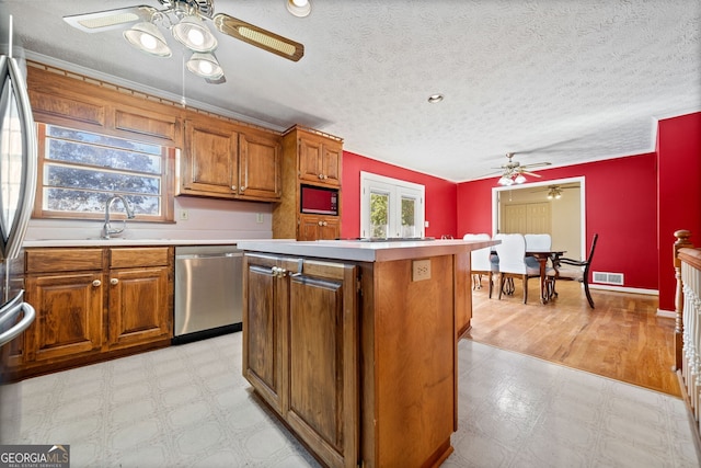 kitchen featuring dishwasher, black microwave, a center island, light wood-type flooring, and a textured ceiling