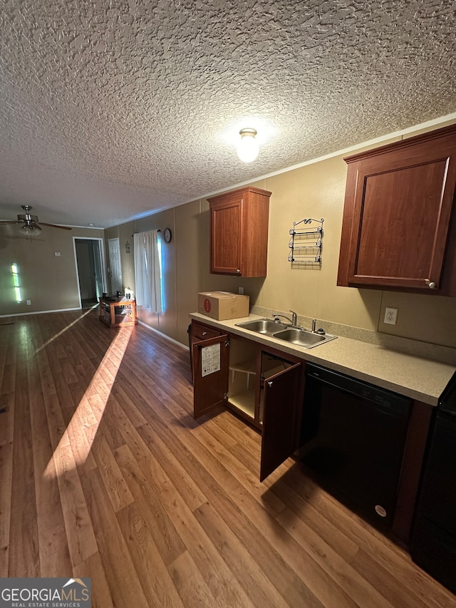 kitchen featuring black dishwasher, sink, a textured ceiling, and light wood-type flooring