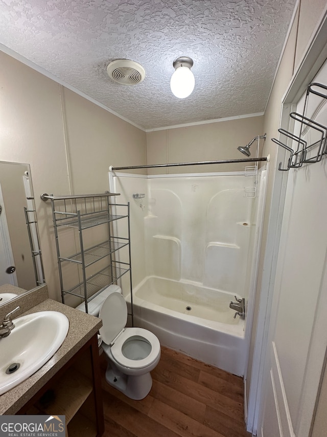 full bathroom featuring a textured ceiling, hardwood / wood-style flooring, toilet, vanity, and shower / bath combination