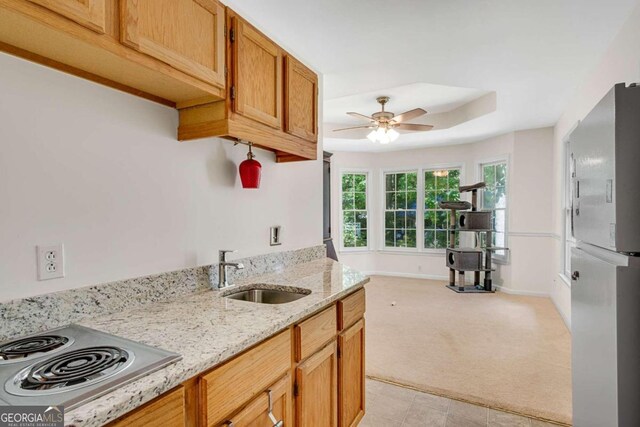 kitchen featuring light carpet, stainless steel fridge, light stone counters, ceiling fan, and sink