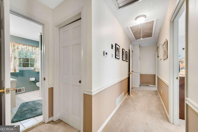 corridor featuring light carpet and a textured ceiling