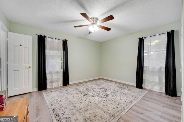 empty room featuring ceiling fan, a textured ceiling, and light wood-type flooring