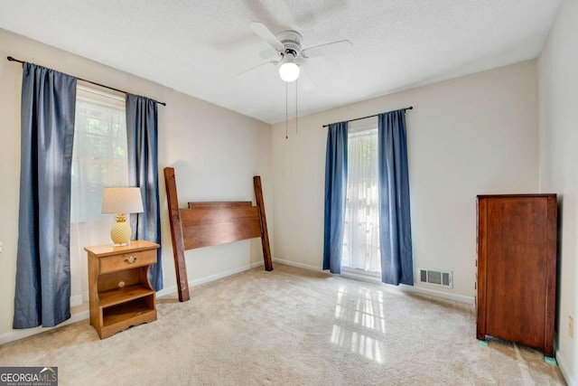 carpeted bedroom with multiple windows, a textured ceiling, and ceiling fan