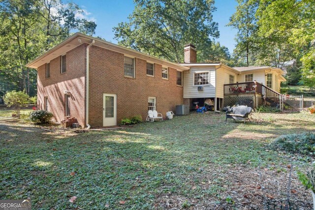 rear view of property with a yard, central AC, and a deck