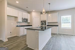 319 Brooks Dr Unit 73, Fairburn, GA 30213 - kitchen with stainless steel microwave, baseboards, dark countertops, white cabinets, and recessed lighting