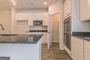 kitchen featuring white cabinetry, dark stone countertops, and appliances with stainless steel finishes