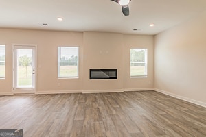 unfurnished living room with ceiling fan, a healthy amount of sunlight, and wood-type flooring