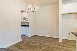 unfurnished dining area featuring dark wood-type flooring and a notable chandelier