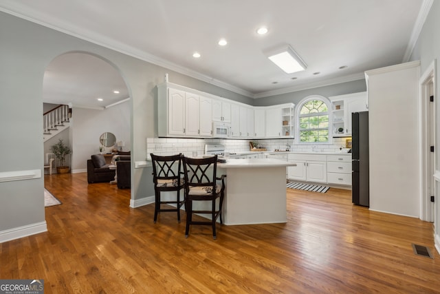 kitchen with white appliances, light hardwood / wood-style flooring, kitchen peninsula, and white cabinets