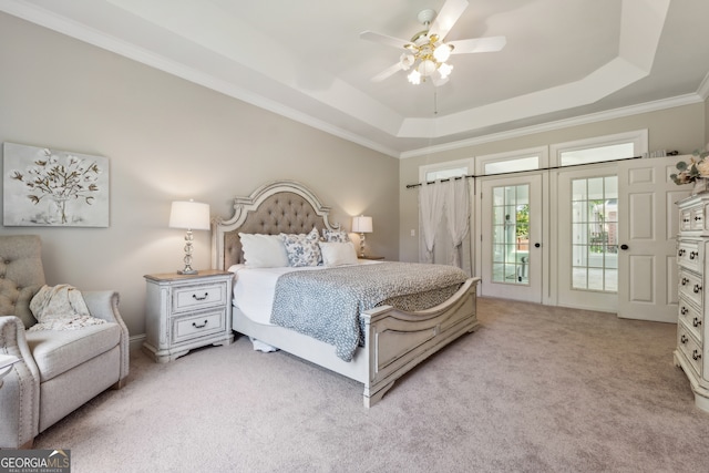 carpeted bedroom with access to outside, ornamental molding, a tray ceiling, and ceiling fan