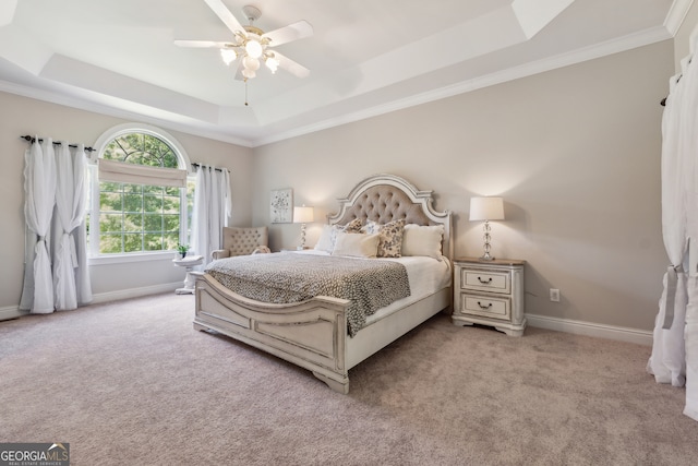 carpeted bedroom with crown molding, a tray ceiling, and ceiling fan