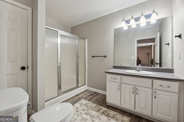 bathroom featuring a shower with door, toilet, hardwood / wood-style flooring, and vanity