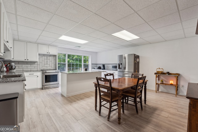 dining space featuring sink, a paneled ceiling, and light hardwood / wood-style flooring