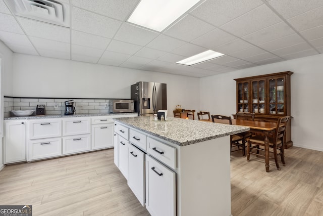 kitchen with light hardwood / wood-style floors, white cabinetry, stainless steel appliances, and a kitchen island