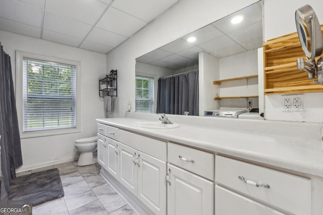 bathroom with vanity, a drop ceiling, toilet, and a wealth of natural light