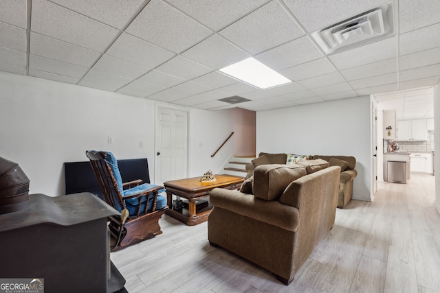 living room with a paneled ceiling and light hardwood / wood-style flooring