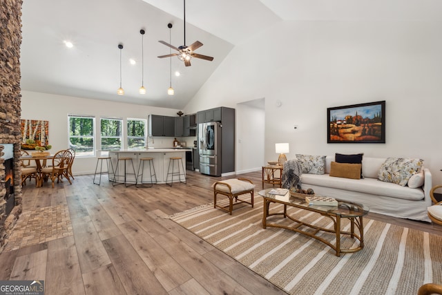 living room with light hardwood / wood-style floors, high vaulted ceiling, and ceiling fan