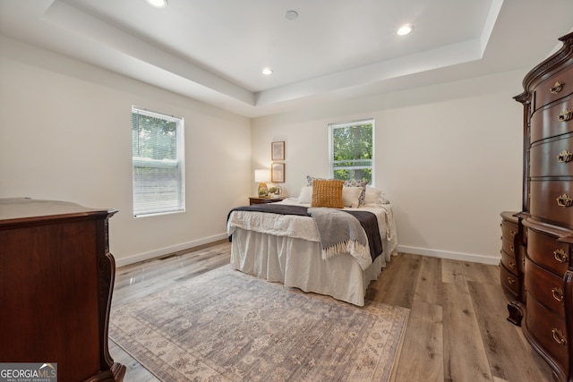 bedroom featuring a tray ceiling and light wood-type flooring