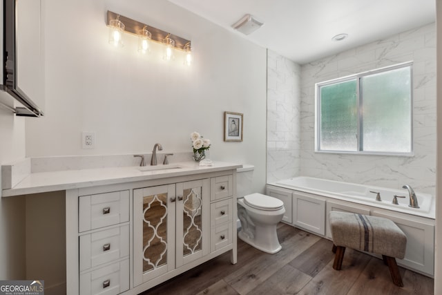 bathroom featuring vanity, hardwood / wood-style floors, toilet, and a bath