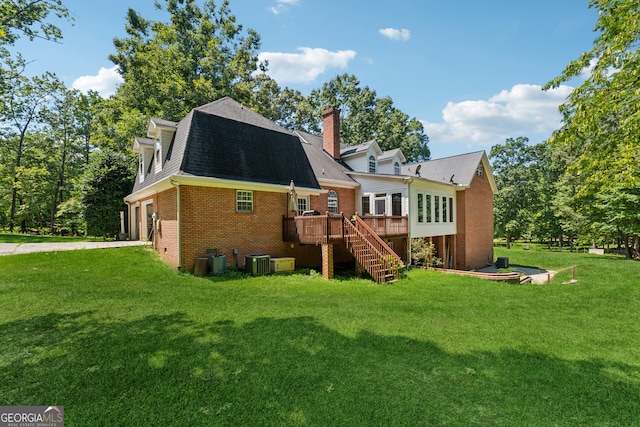 rear view of property featuring a deck, a lawn, and central AC