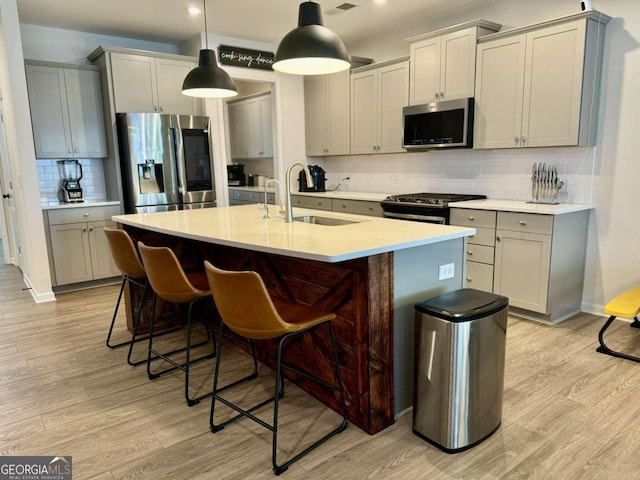 kitchen featuring backsplash, stainless steel appliances, sink, and light wood-type flooring