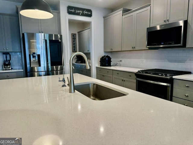 kitchen with appliances with stainless steel finishes, gray cabinetry, sink, and backsplash