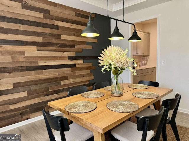 dining space featuring ornamental molding, light hardwood / wood-style flooring, and wood walls