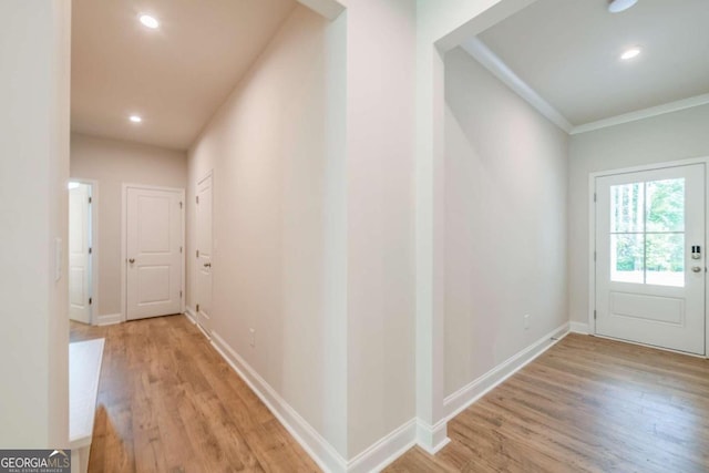 hall with light hardwood / wood-style floors and ornamental molding