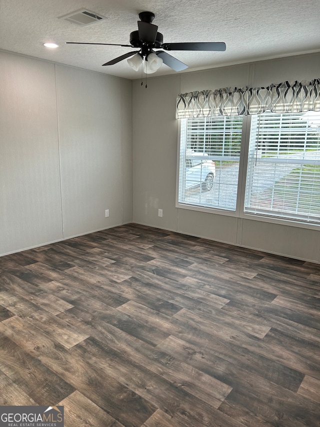 spare room with dark hardwood / wood-style floors, a textured ceiling, and ceiling fan