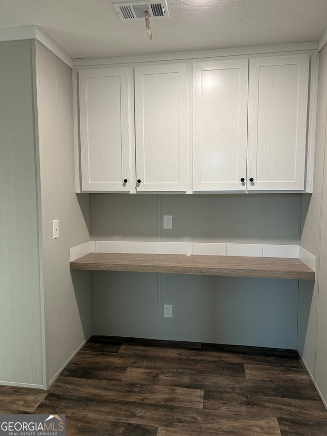 unfurnished office featuring built in desk and dark hardwood / wood-style floors