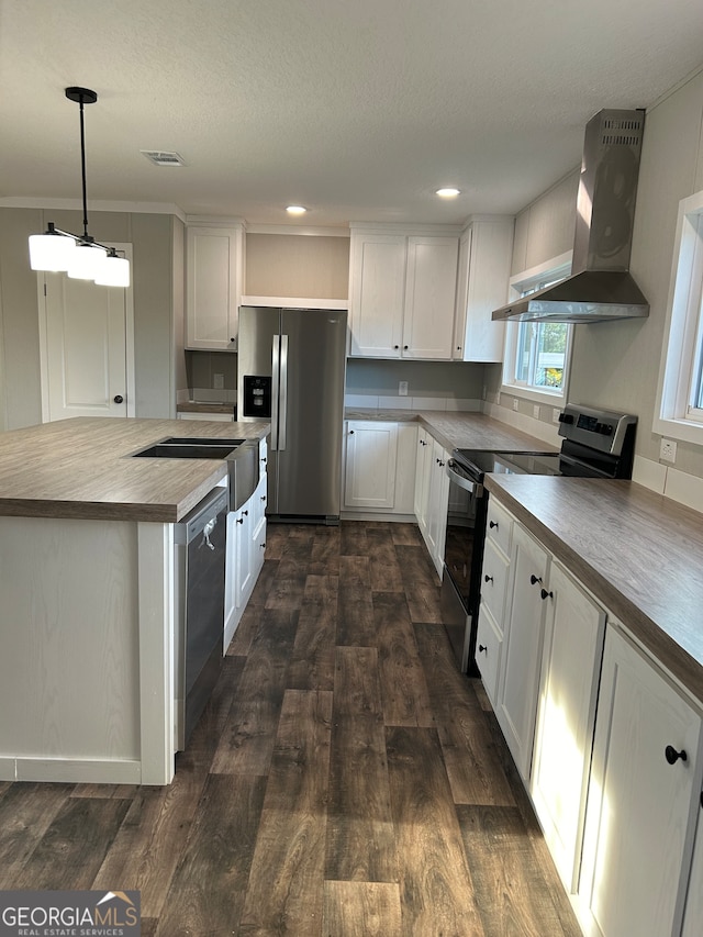 kitchen featuring wall chimney range hood, pendant lighting, white cabinetry, appliances with stainless steel finishes, and dark hardwood / wood-style flooring