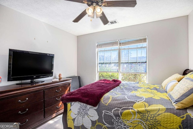 carpeted bedroom with ceiling fan and a textured ceiling