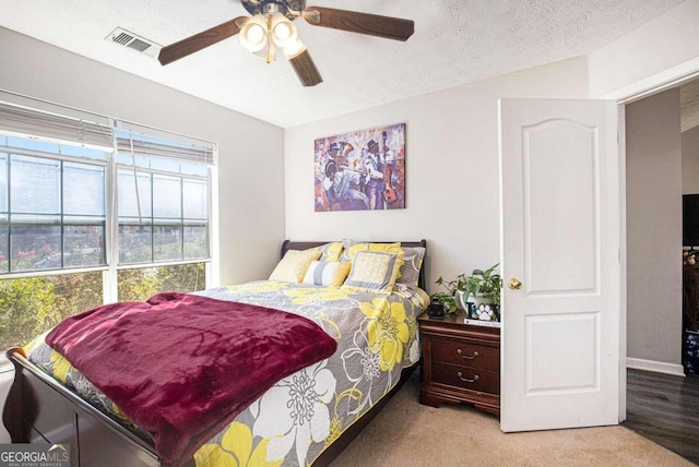 bedroom with a textured ceiling, ceiling fan, and carpet