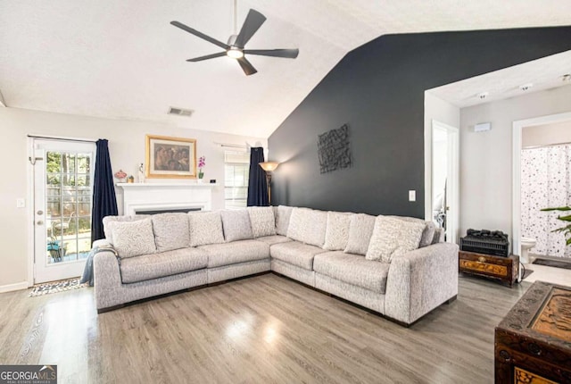 living room with lofted ceiling, hardwood / wood-style flooring, and ceiling fan