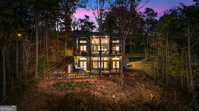 back house at dusk featuring a balcony