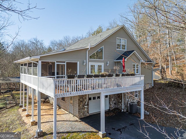 rear view of property with a garage, a sunroom, a wooden deck, and central AC unit