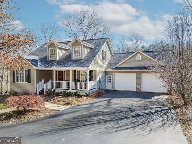 cape cod home featuring covered porch and a garage