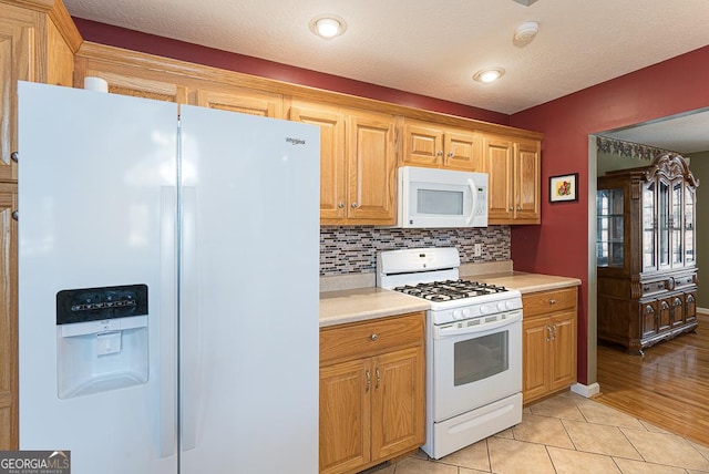 kitchen with light tile patterned floors, decorative backsplash, and white appliances