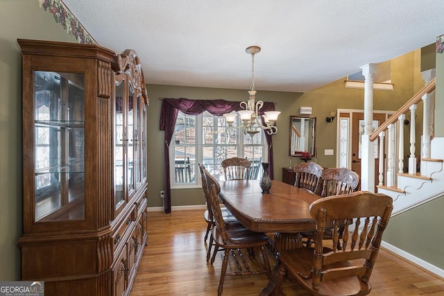 dining area featuring light hardwood / wood-style flooring, a notable chandelier, and ornate columns