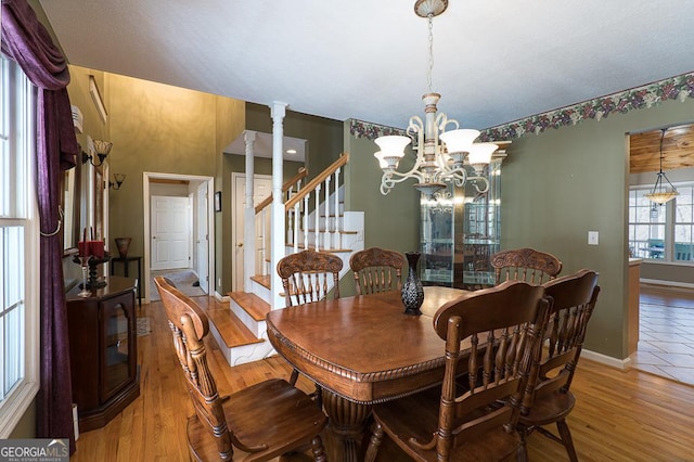 dining area featuring ornate columns, wood-type flooring, and a notable chandelier